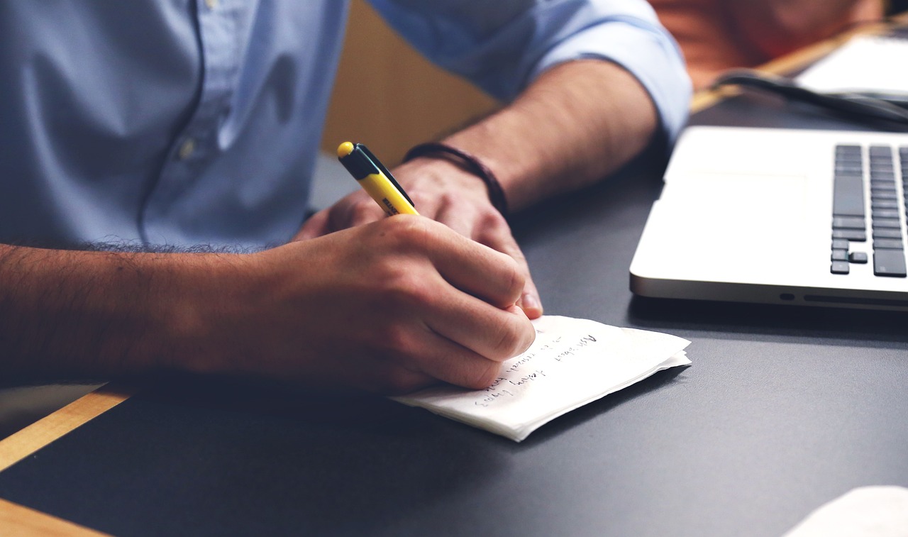 A man with a laptop and writing on a paper